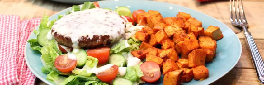 Köstlicher Brötchenloser Burger auf Salat mit Kochkäse und Süßkartoffelwürfeln